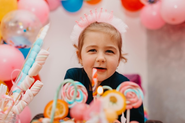 Ragazza con la sua torta di compleanno carda di buon compleanno la bambina carina festeggia il compleanno circondata da regali