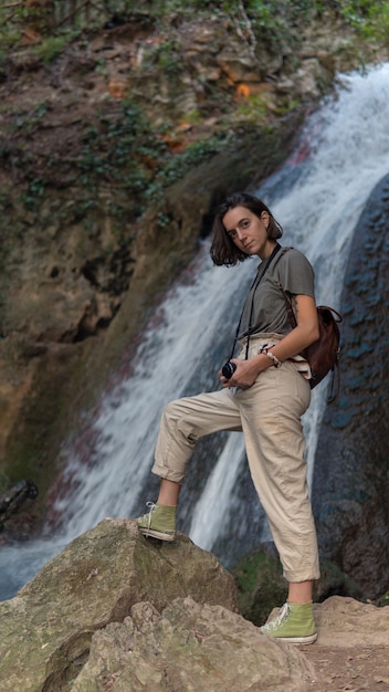 A girl with her camera at the bottom of a waterfall