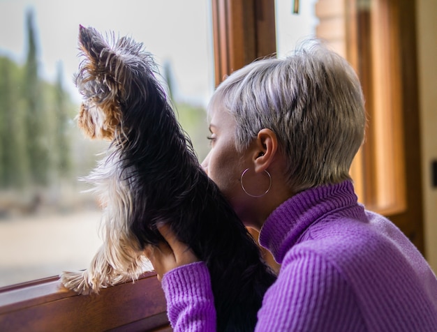 写真 窓の閉じ込めの外を見ている彼女の犬を持つ少女