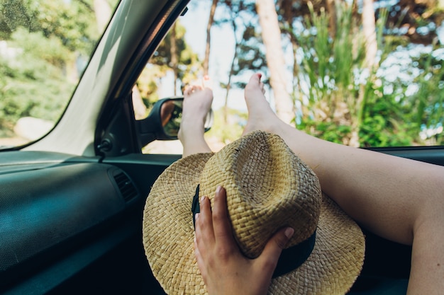 Girl with her feet out of the window of the car sunbathing on a summer afternoon, 