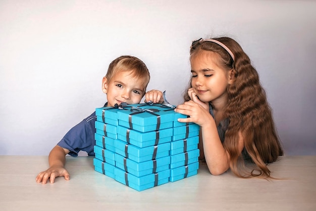 Фото Девочка со своим младшим братом возле огромной кучи подарочных ящиков