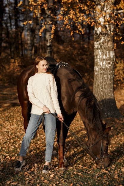 自然の中で馬を持った少女、動物と一緒に秋の散歩