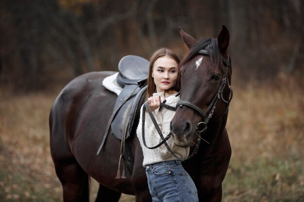 自然の中で馬を持った少女、動物と一緒に秋の散歩