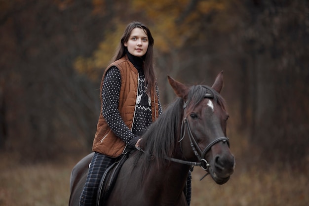 自然の中で馬を持った少女、動物と一緒に秋の散歩