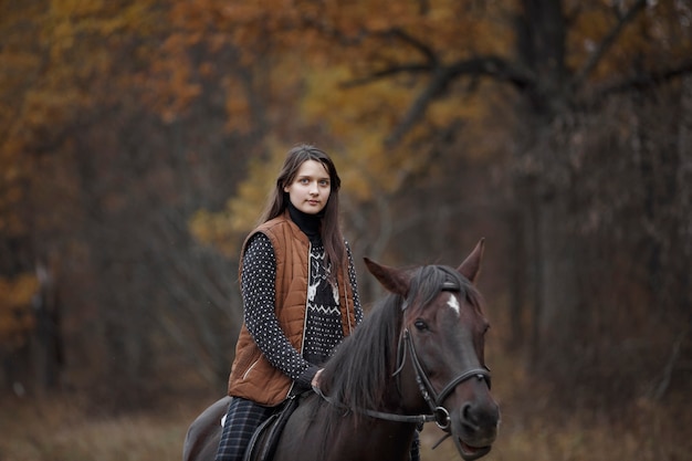 自然の中で馬を持った少女、動物と一緒に秋の散歩