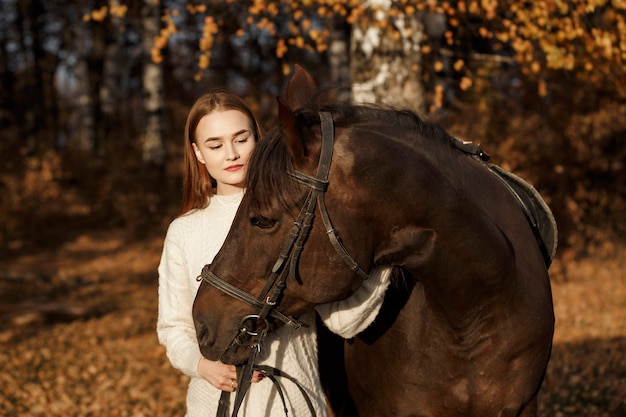 自然の中で馬を持った少女、動物と一緒に秋の散歩