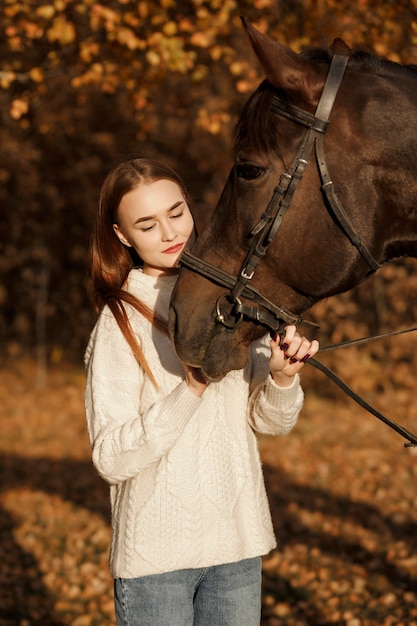 自然の中で馬を持った少女、動物と一緒に秋の散歩