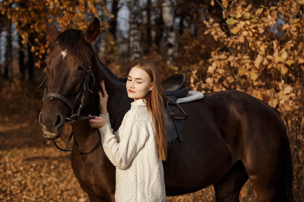 自然の中で馬を持った少女、動物と一緒に秋の散歩