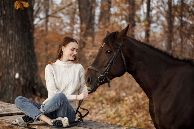 自然の中で馬を持った少女、動物と一緒に秋の散歩