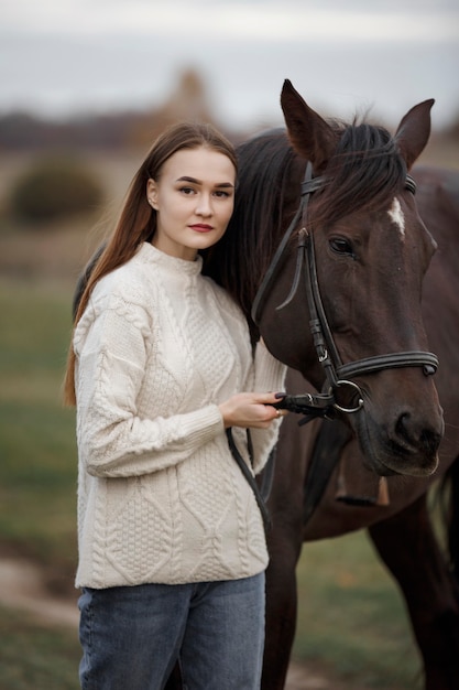 自然の中で馬を持った少女、動物と一緒に秋の散歩