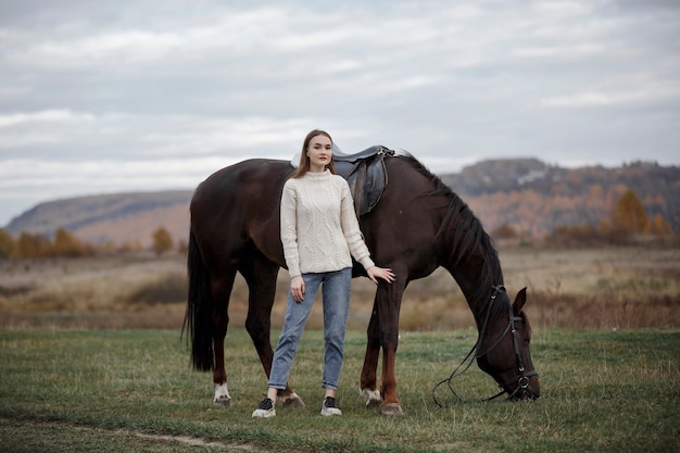 A girl with a horse in nature, an autumn walk with an animal