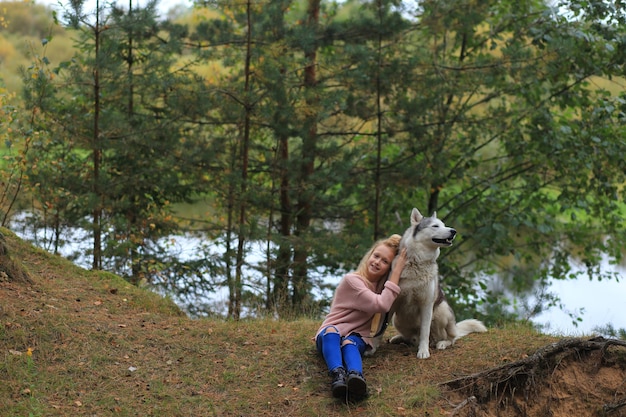 A girl with a husky walks in the forest.