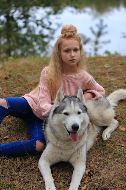 A girl with a husky walks in the forest