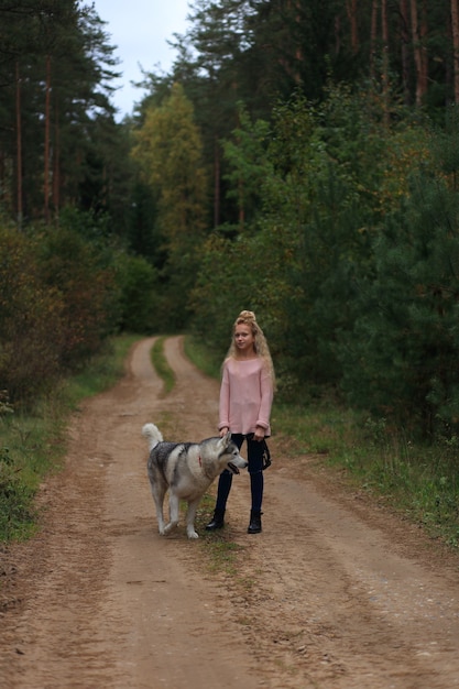 A girl with a husky walks in the forest