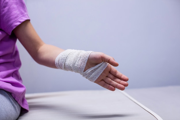 Girl with injured hand sitting on stretcher bed