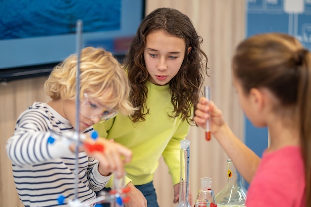 Girl with interest watching classmates with test tubes