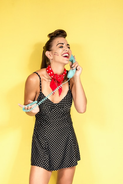 Photo girl with landline telephone on yellow background with pop art retro poster make up style