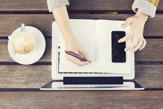 Photo girl with laptop blank diary cell phone and coffee mug on wooden table