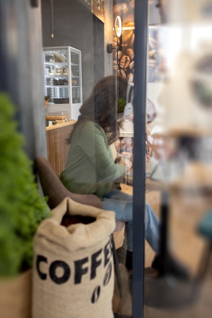 Una ragazza con un computer portatile in un caffè dietro il vetro l'interno del caffè