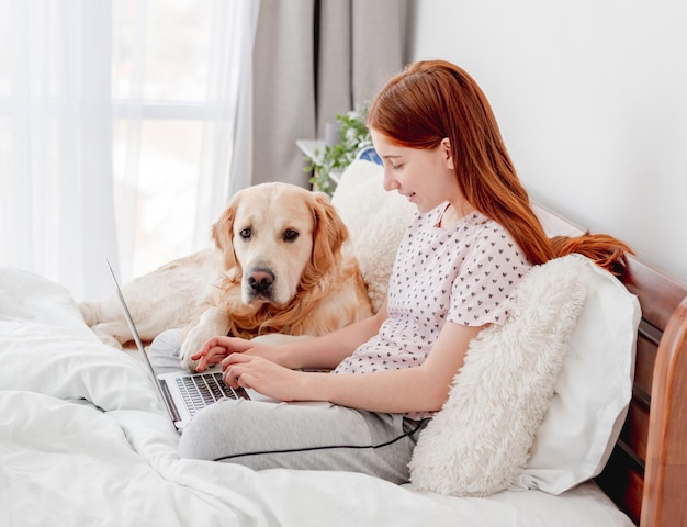 Girl with laptop and golden retriever dog