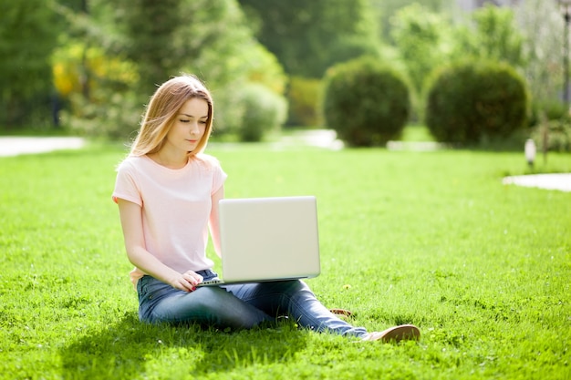 Girl with a laptop sitting on the lawn