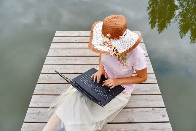 Girl with a laptop on a wooden pier 