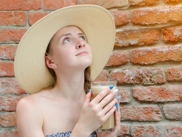 Girl with latte in hand and in a hat looking up