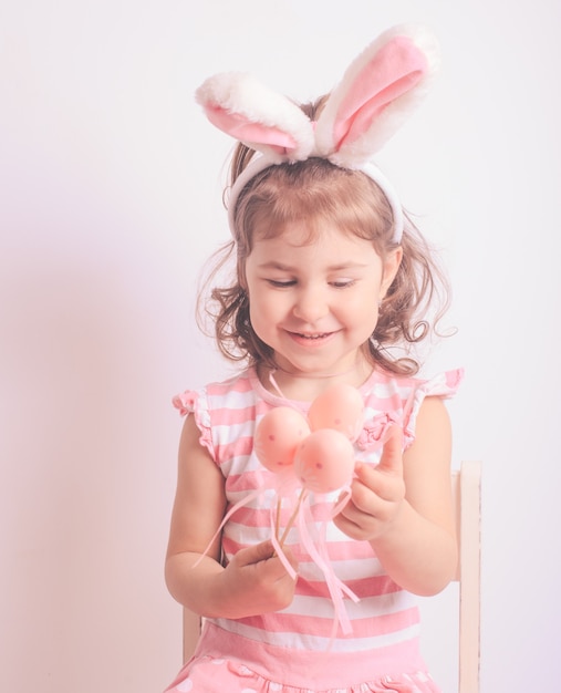 Bambina con gli ovetti rosa per la caccia di pasqua