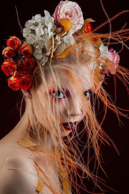 活気のある巻き毛と花を頭に抱えた少女。アートオブジェクト。フラワーガールの妖精