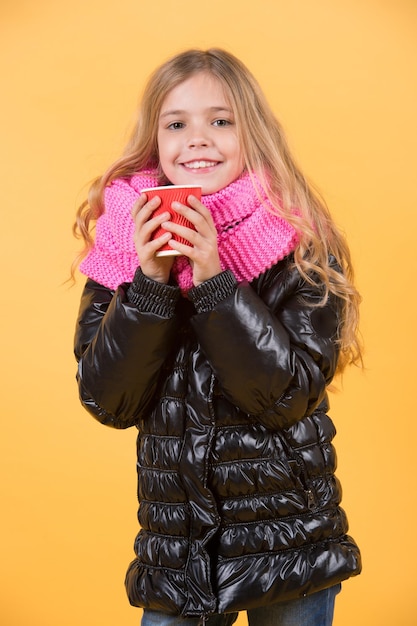 Girl with long blond hair in black jacket hold mug