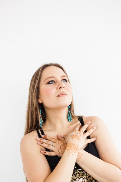 A girl with long blond hair in dark clothes, beauty, self-care, henna drawing on her hands, traditions