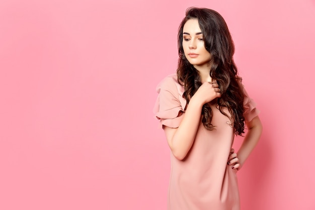 Girl with long curly hair in a pink dress.