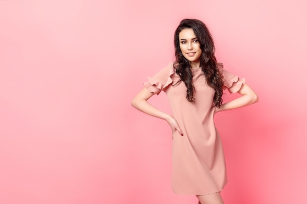 Girl with long curly hair in a pink dress.