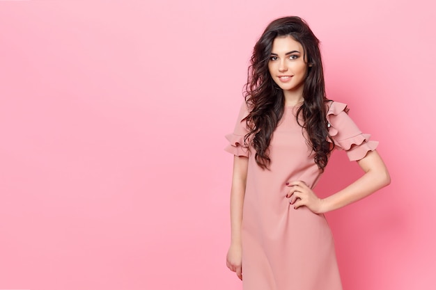 Girl with long curly hair in a pink dress.