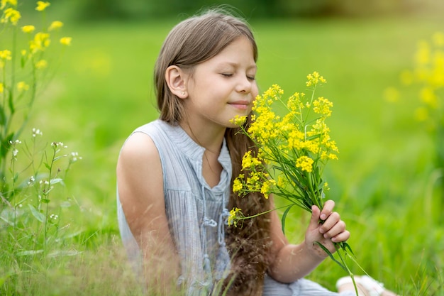 A girl with long hair in a field sniffing yellow flowers High quality