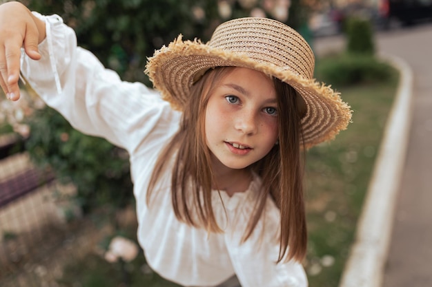 Girl with long hair and freckles in a straw hat enjoys life and summer