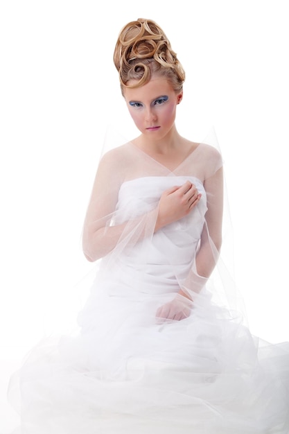 The girl with long hair in a light white dress posing on light grey background Studio shotisolated image