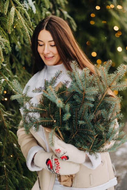 A girl with long hair in winter on the street with a bouquet of fresh fir branches