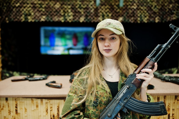 Girl with machine gun at hands on shooting range.
