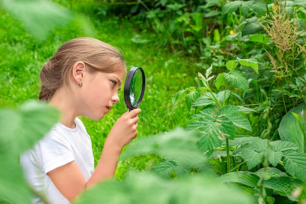 a girl with a magnifying glass examines the plants in the garden
