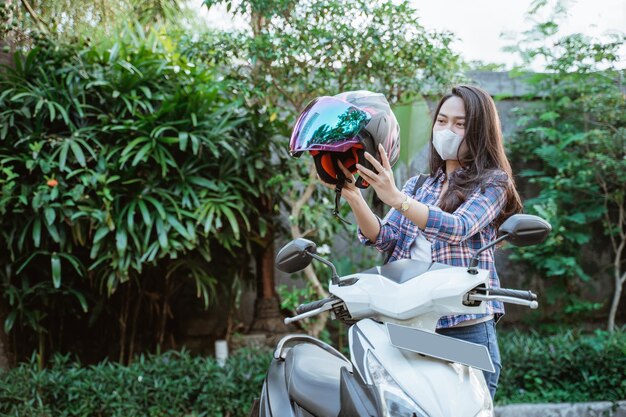 コピースペースでバイクに乗る前にヘルメットをかぶったマスクを持つ少女