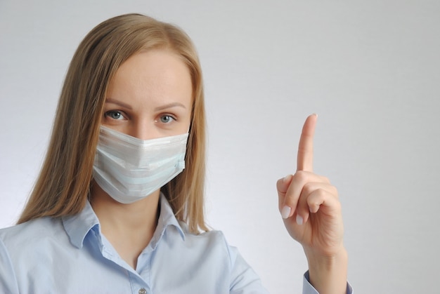 Girl with medical mask points finger up