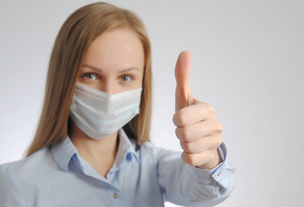 Girl with medical mask shows thumb up