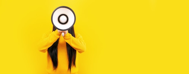 Photo girl with a megaphone on a yellow space