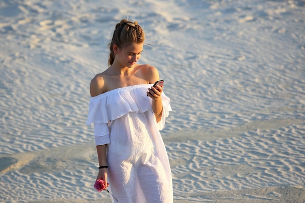 Girl with mobile phone in hand on the sand