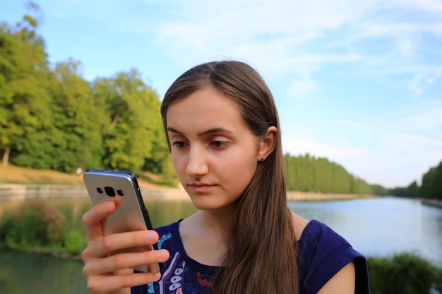 携帯電話を持った女の子が公園でメッセージを読む