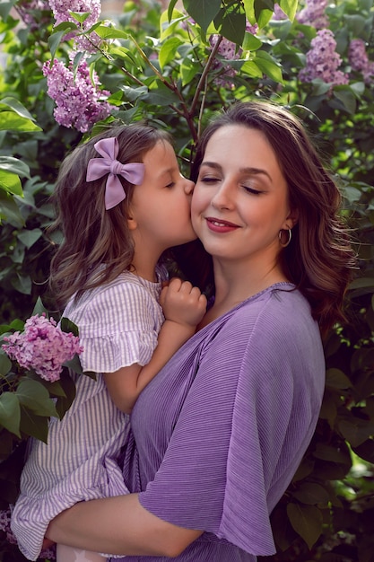 Photo girl with mom in lilac dresses stand next to the lilac