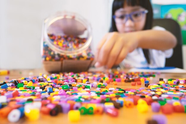 Photo girl with multi colored beads on table at home