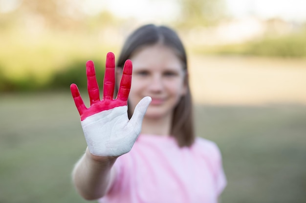 인도네시아 국기 색상으로 칠해진 열린 손을 가진 소녀는 손 소녀 쇼 중지 제스처에 초점을 맞춥니다.