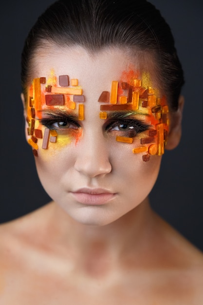 Photo girl with orange and red rhinestones on her face.